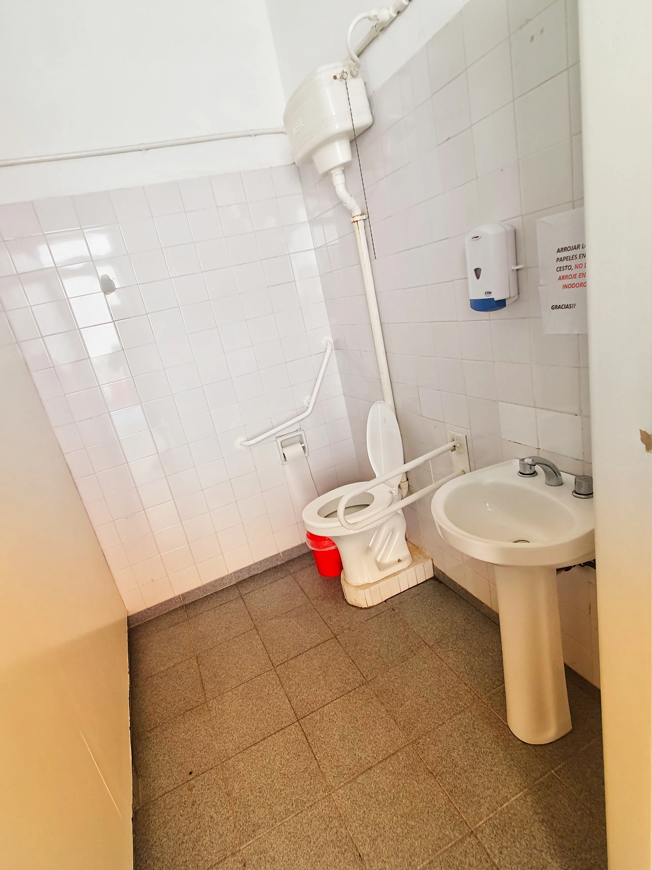 Baño adaptado con barrales de apoyo junto al inodoro y al lavatorio