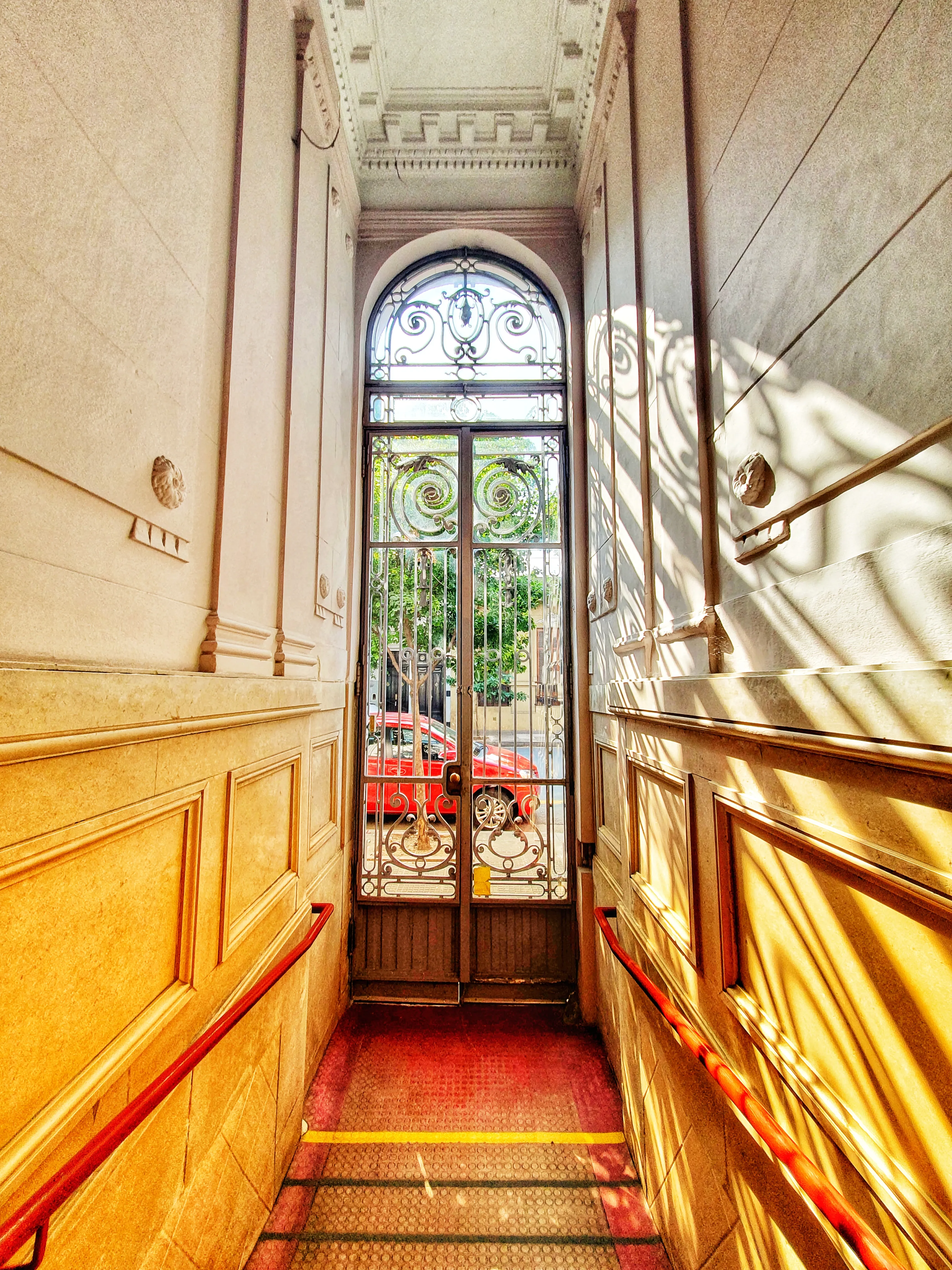 Entrada del centro con puerta de hierro forjado bajo un arco de vidrio