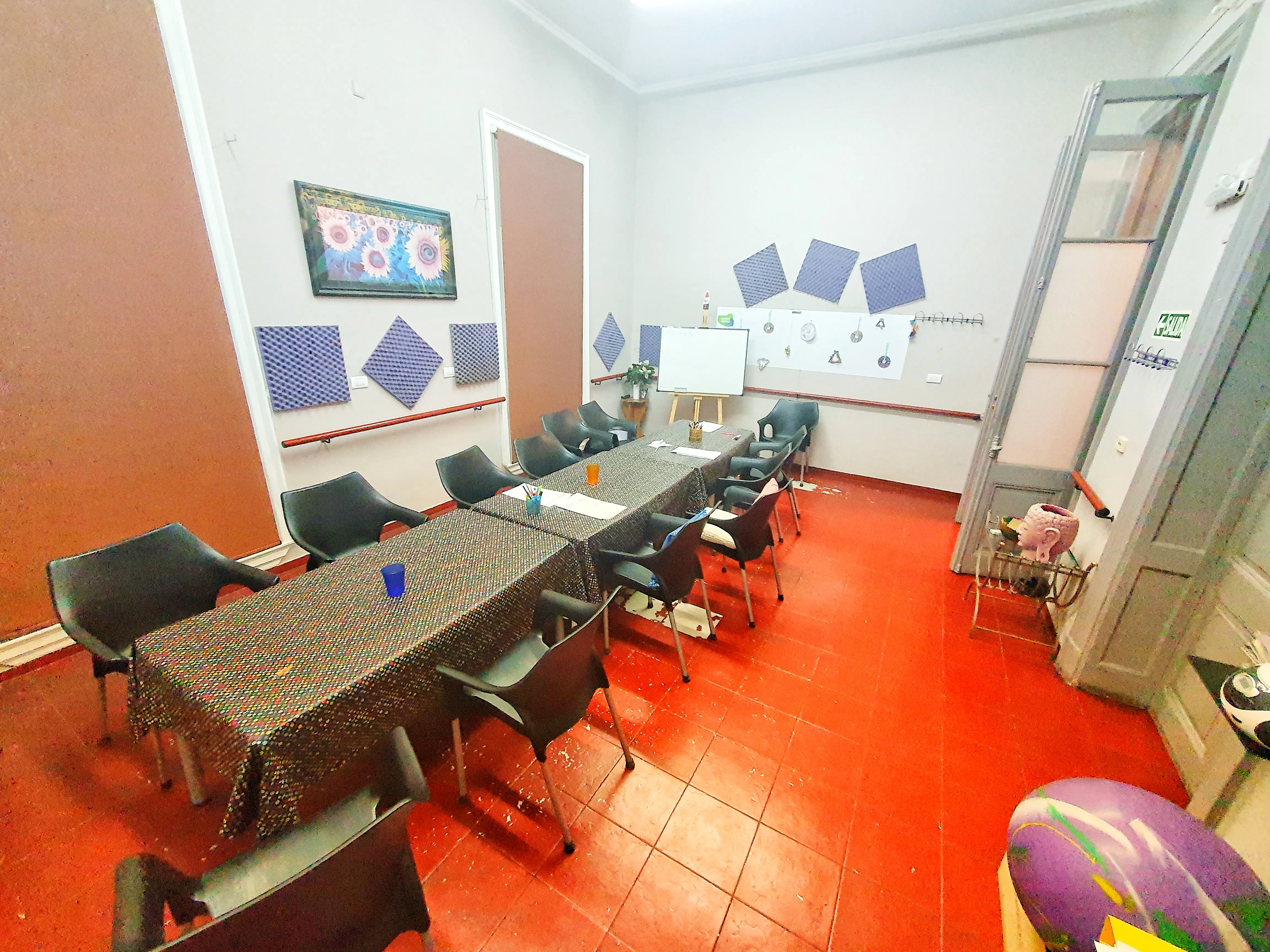 Sala de talleres con mesas largas, sillas y una pizarra