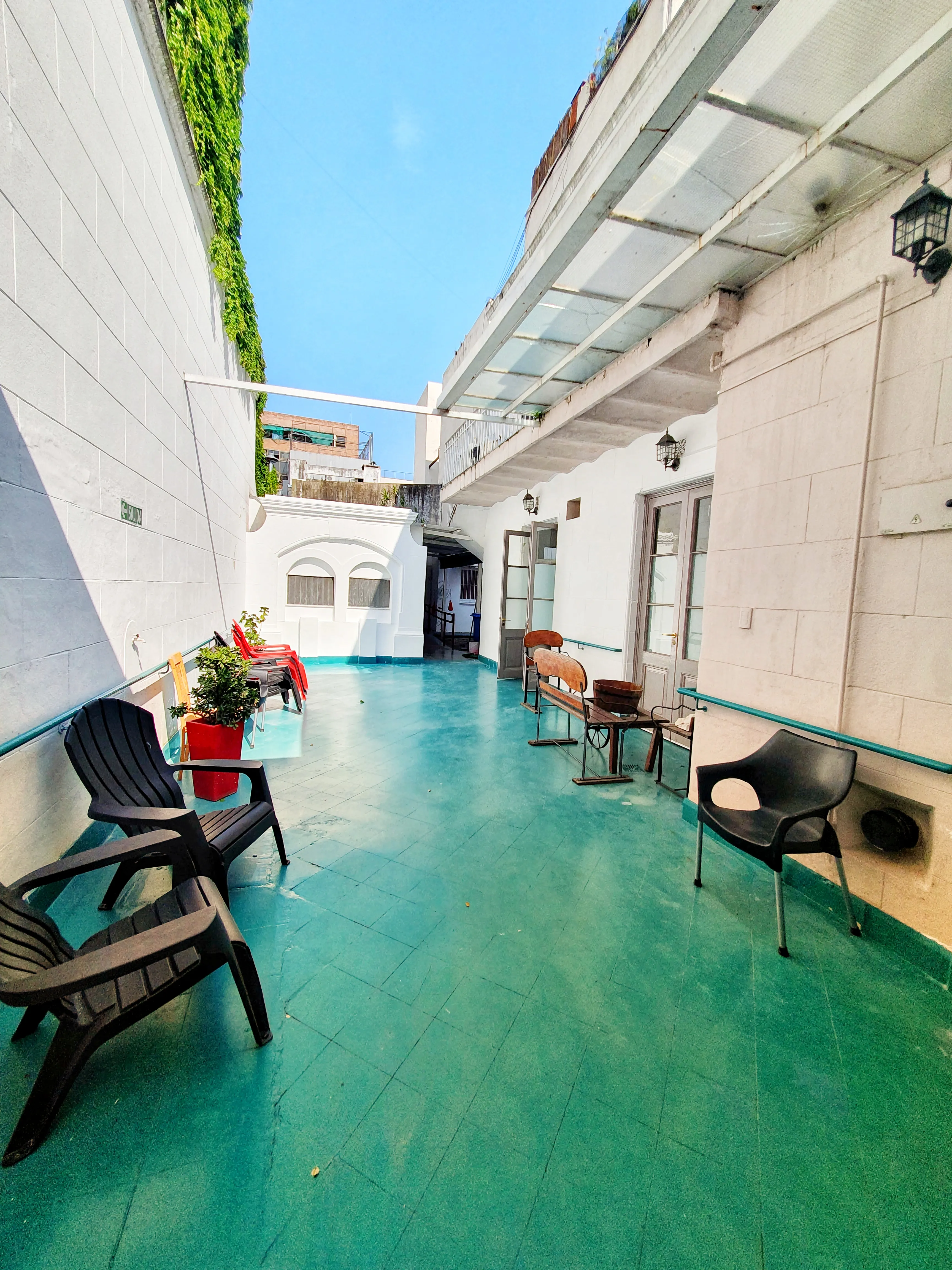 Patio al aire libre con piso verde agua, reposeras y una enredadera
