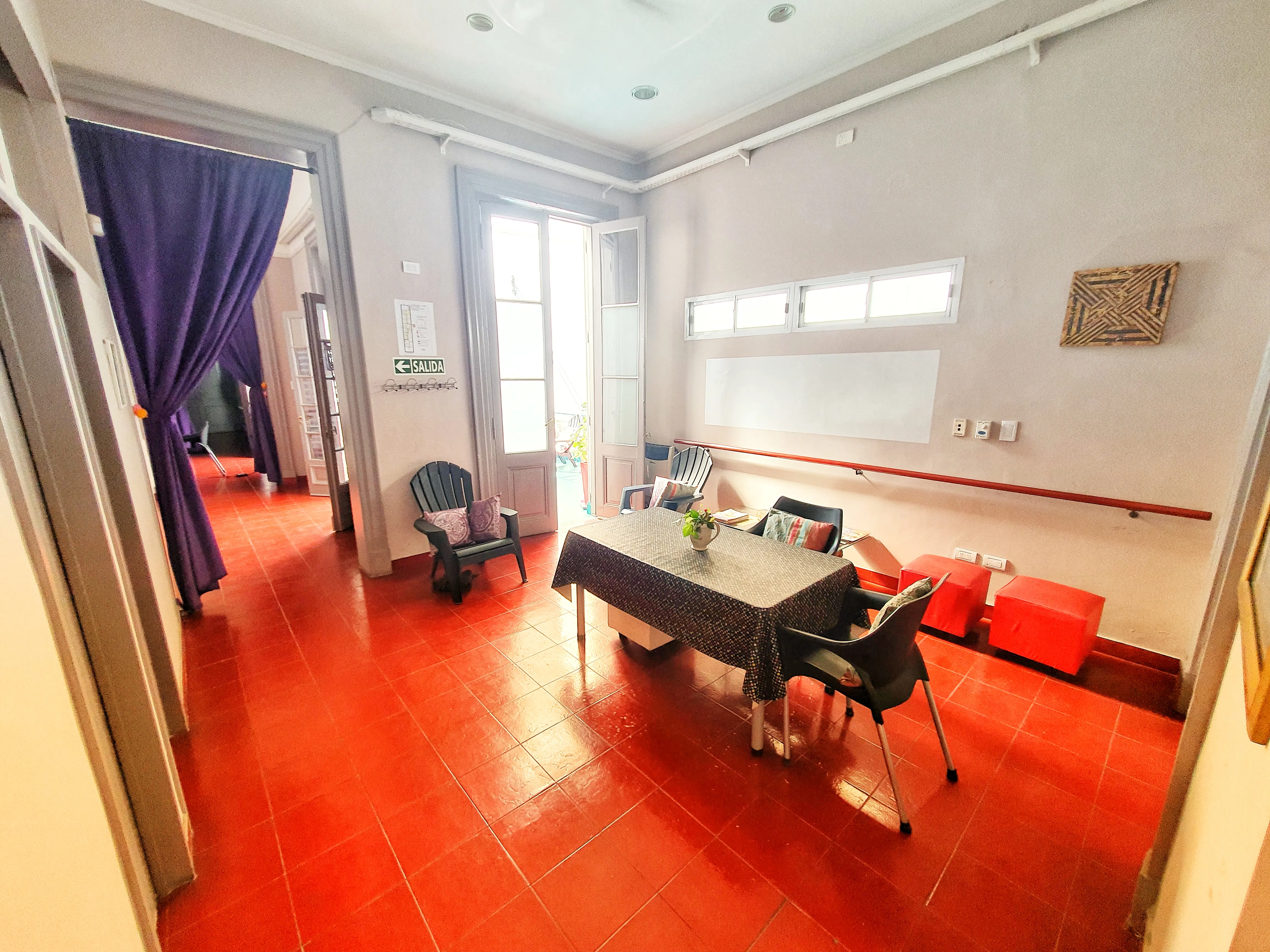 Sala de estar con mesa de trabajo y cortinados violetas